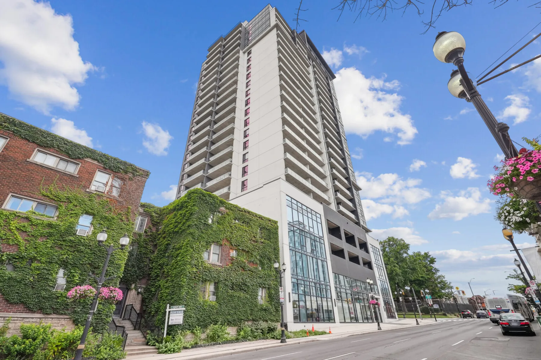 A modern condo tower beside a heritage brick building on an Ontario main street